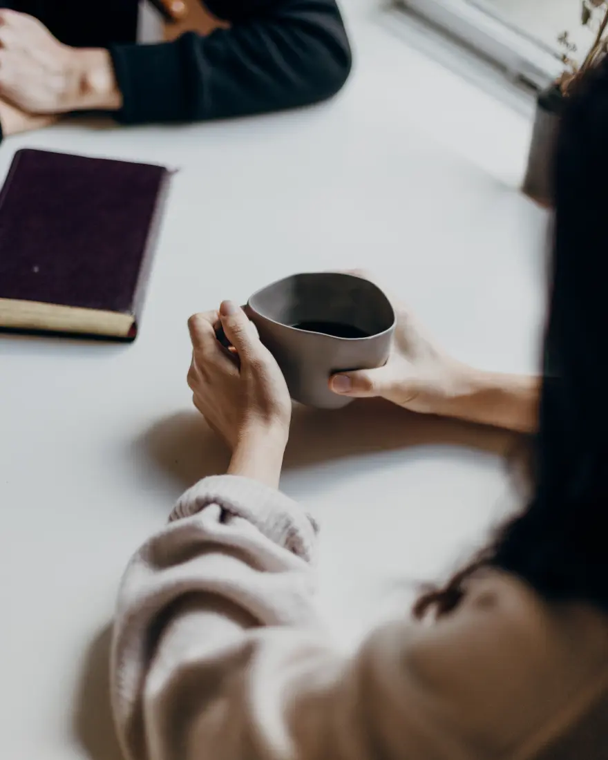 Two people sitting at a table having a conversation over a hot beverage
