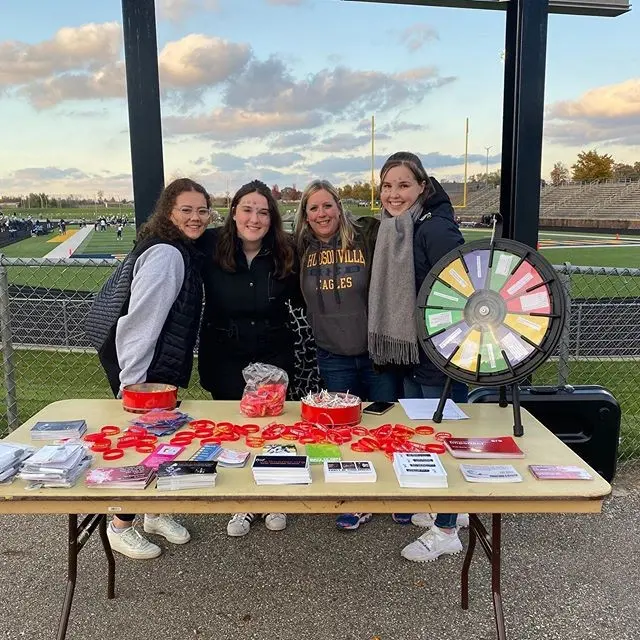 Students standing at a table with Red Ribbon Week promotional items