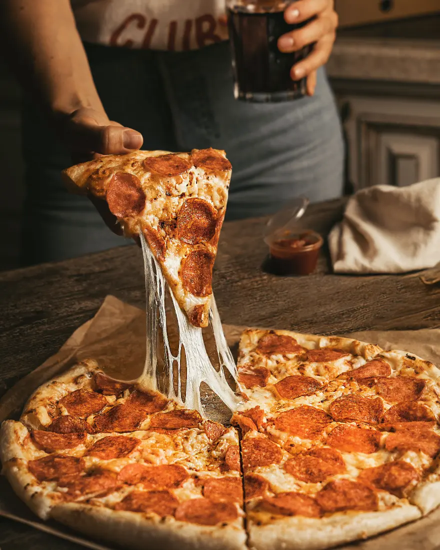 Person picking up slice of pizza